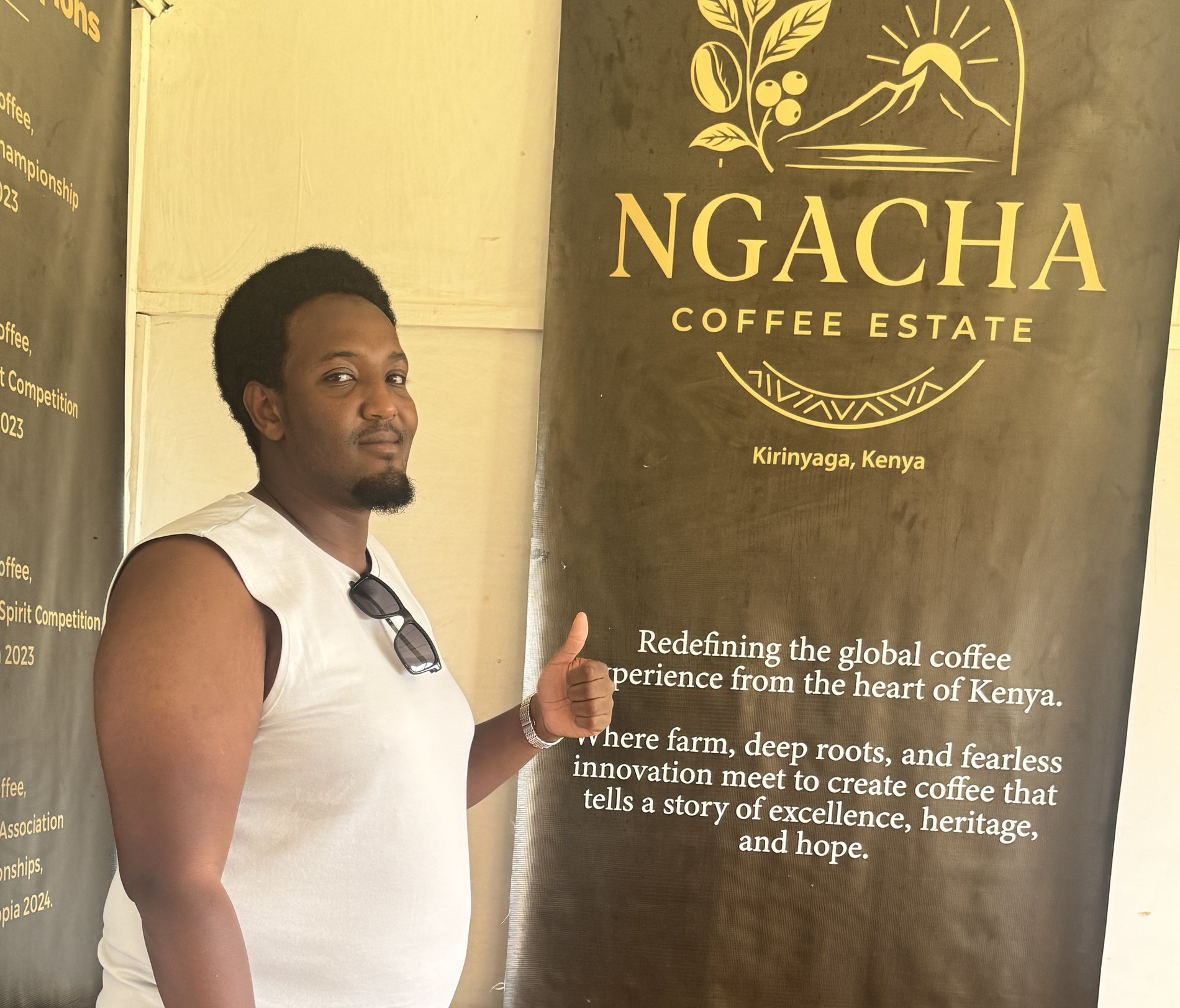 The Ngacha Coffee Estate sign in Kirinyaga, Kenya, beside a producer at the estate